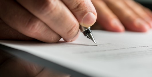 Closeup of male hand about to sign a business contract with a fountain pen.